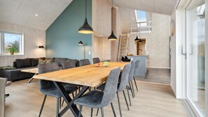 Ein moderner Wohnraum mit einem Holzesstisch, grau gepolsterten Stühlen, einem grauen Sofa und einer blauen Akzentwand.