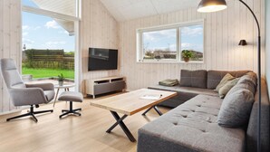 Ein modernes Wohnzimmer mit Fernseher, Sofa und Couchtisch.