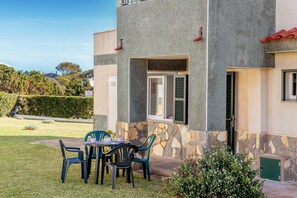 A building with a stone facade, a balcony, and a patio with a table and chairs.