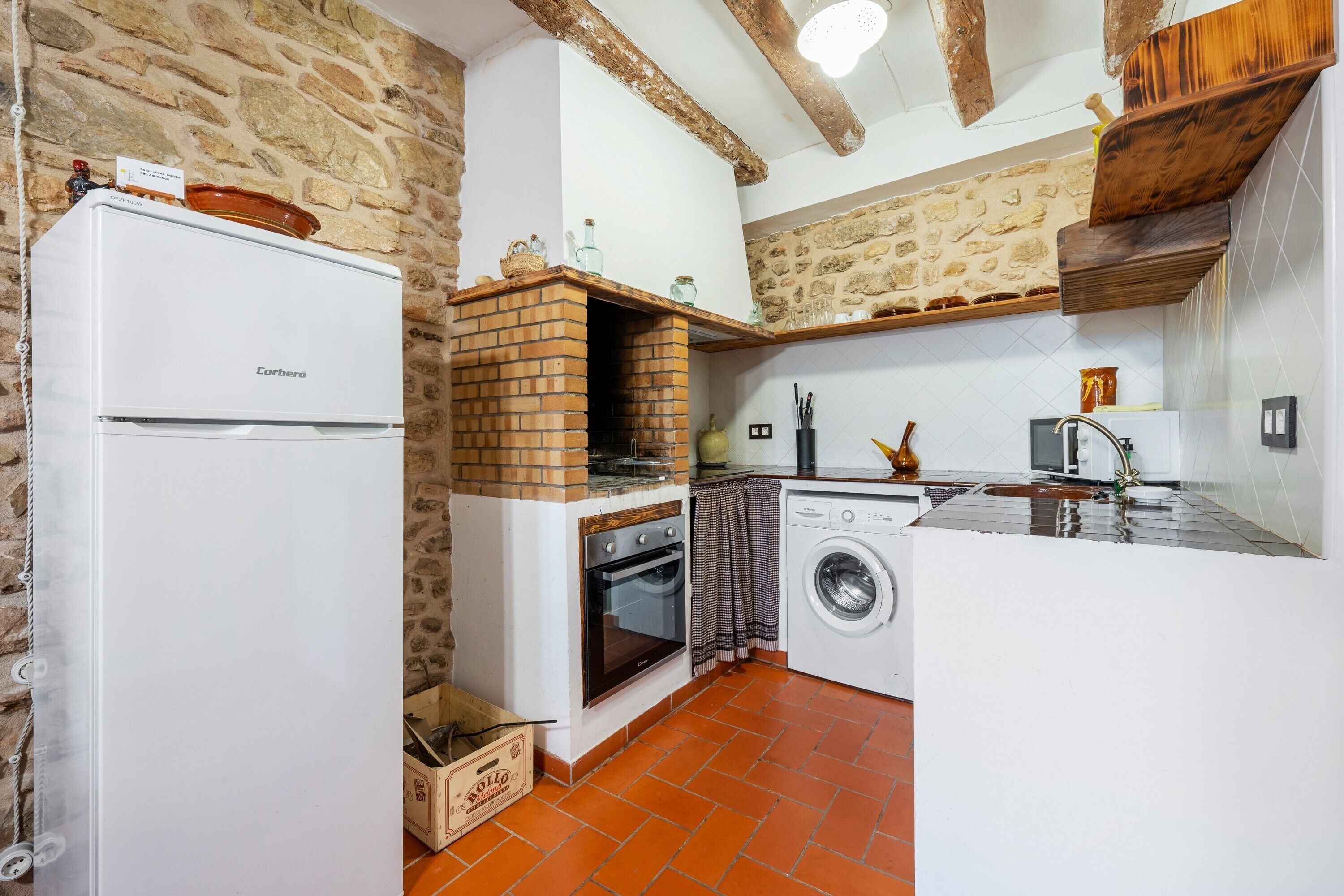 A compact kitchen with a brick oven, washing machine, and a refrigerator.