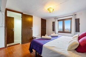 Une chambre à coucher avec un lit, une fenêtre donnant sur un paysage agréable, une porte et un luminaire au plafond.