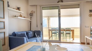 A living room with a sofa, a coffee table with a vase and candle holders, a dining area with chairs and a table, and a sliding glass door leading to a balcony. - N269 - Numana, single four-room villa with garden (Numana)
