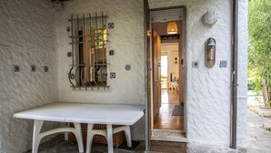 A stone-floored entrance with a white bench, a metal gate, and a door leading inside. - N269 - Numana, single four-room villa with garden (Numana)