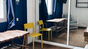 A room with a wooden table, two yellow chairs, a wicker chair, and a view through a glass door. - Altea Lodge (San Rafael del Yuma)