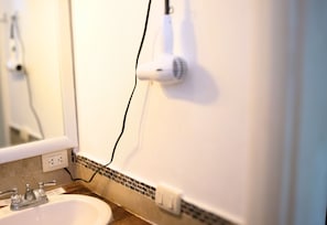 A bathroom with a sink, mirror, and a hair dryer plugged in. - Altea Lodge (San Rafael del Yuma)