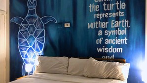 A bedroom with a bed, a wall with a turtle mural, and a door with a sign. - Altea Lodge (San Rafael del Yuma)
