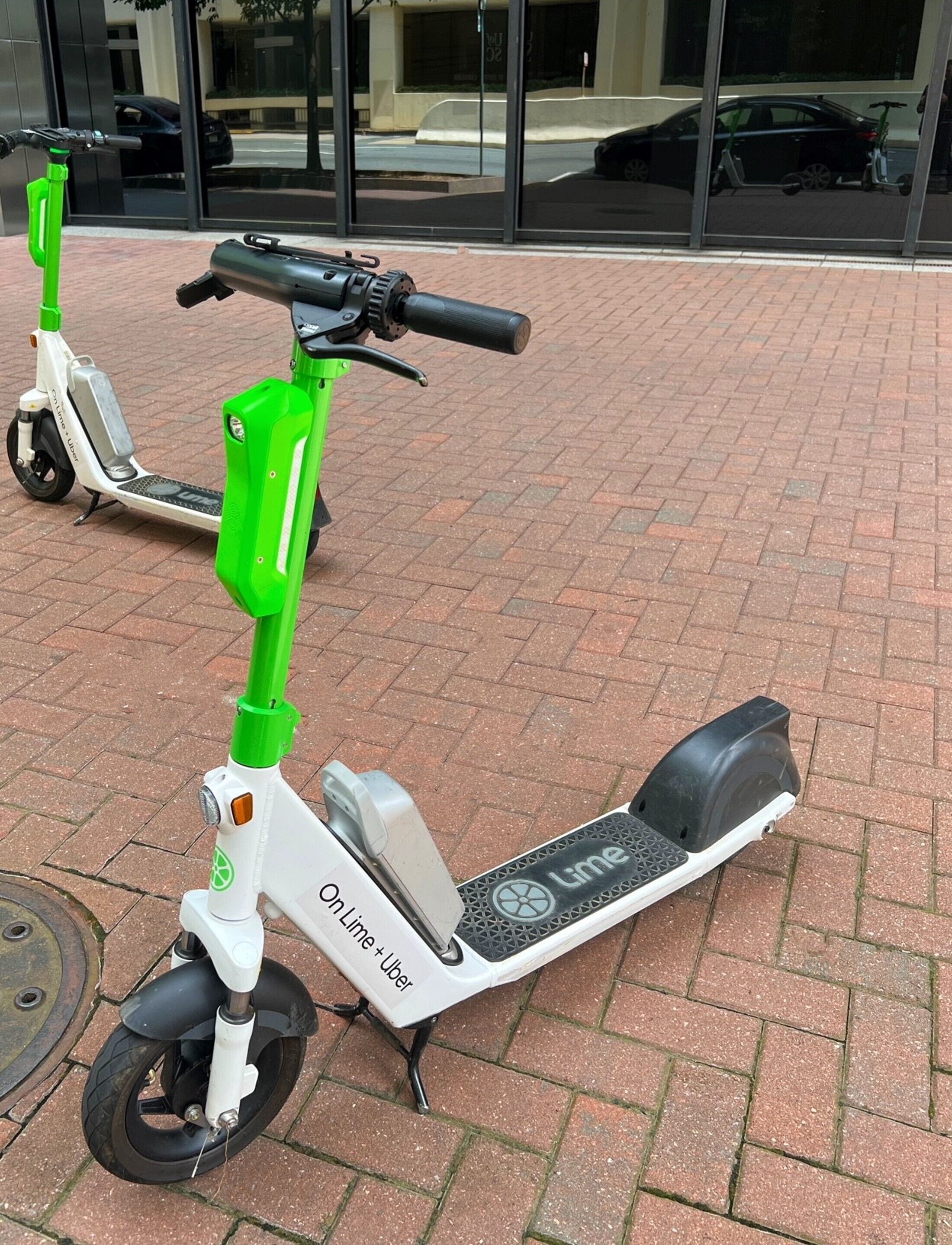 A lime scooter parked on a brick pavement.