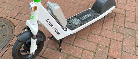 A lime scooter parked on a brick pavement.