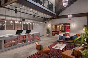 Un lobby moderno con mostrador de recepción, zona de estar y una escalera.