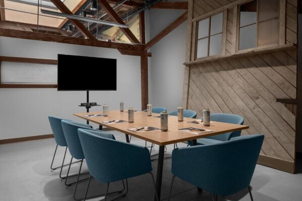 A conference room with a large table, blue chairs, a projector screen, and wooden beams. - Bposhtels SLC (Salt Lake City)