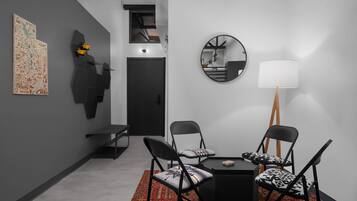 Une pièce moderne avec une table à manger noire, deux chaises, un tapis, un miroir et des œuvres d’art accrochées au mur.