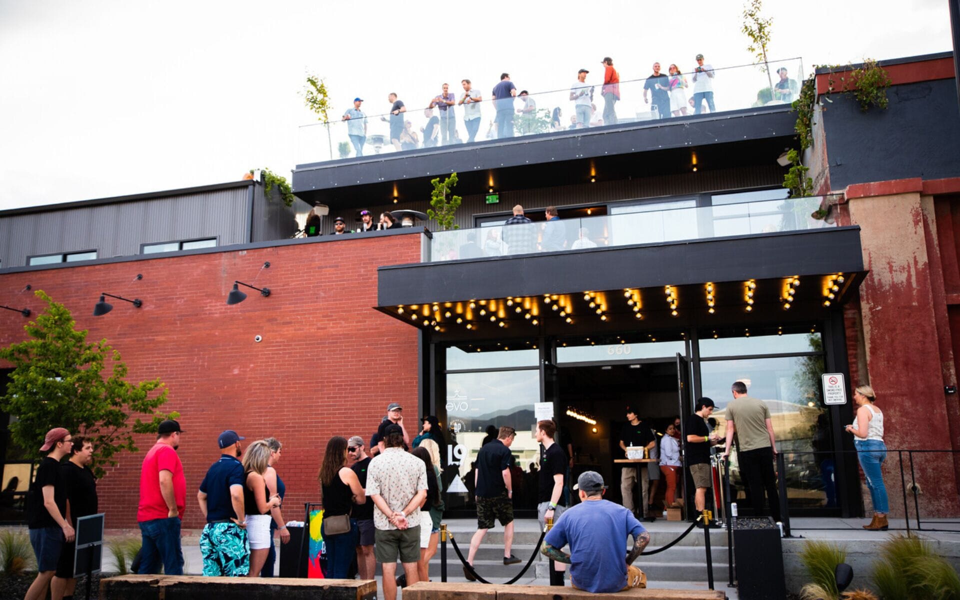 A modern building with a glass facade and a rooftop terrace.