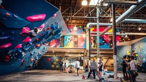 Una palestra di arrampicata indoor con pareti di diverse altezze e un pavimento in legno.