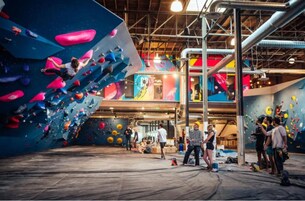 Un gimnasio de escalada en interiores con varias paredes de escalada y piso de madera.