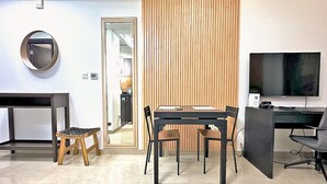 Un espacio de oficina moderno con un escritorio, silla y computadora. Hay un televisor en la pared y un panel divisor de madera.