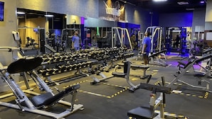 Un gimnasio con diverso equipo de ejercicio, incluyendo mancuernas, bancos y máquinas de pesas.