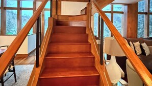 Eine Holztreppe mit Glastrennwand, die zu einer zweiten Etage führt.