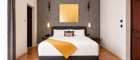 A hotel room with a large bed, a wall-mounted artwork, a wooden floor, and a door.