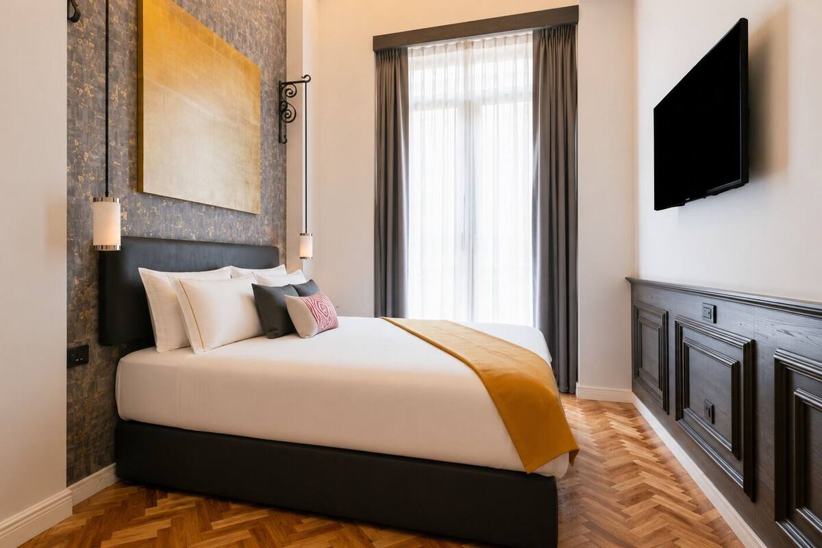A modern hotel room with a large bed, a mounted TV, and a view of the outdoors.
