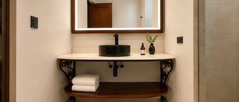 A bathroom with a white sink, a mirror, a towel rack, and a small plant.