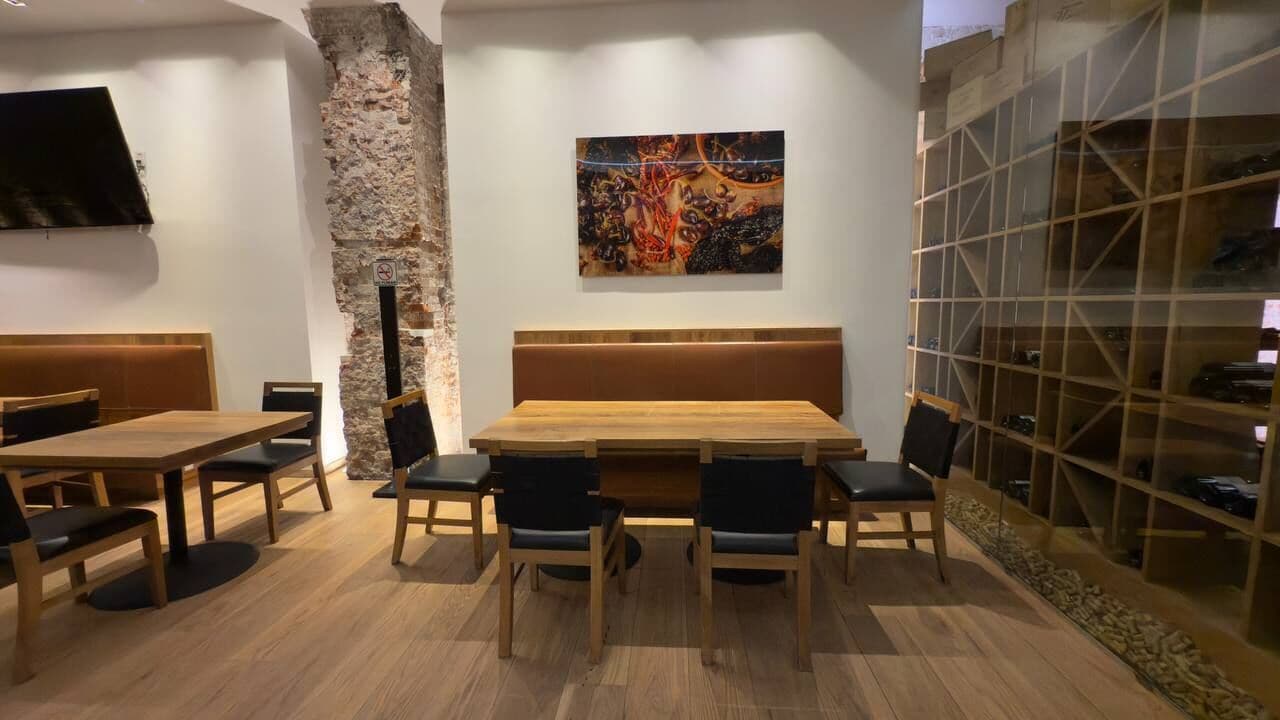A dining area with a wooden table and chairs, a stone accent wall, a mounted painting, and a wine rack.