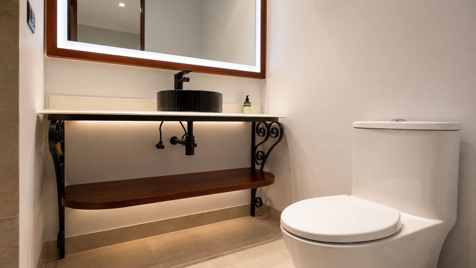 A bathroom with a white toilet, a black sink with a mirror above it, and a wooden shelf below.