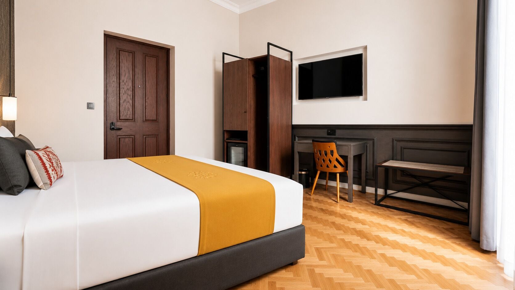 A hotel room with a bed, a desk, a TV, and a wooden floor.