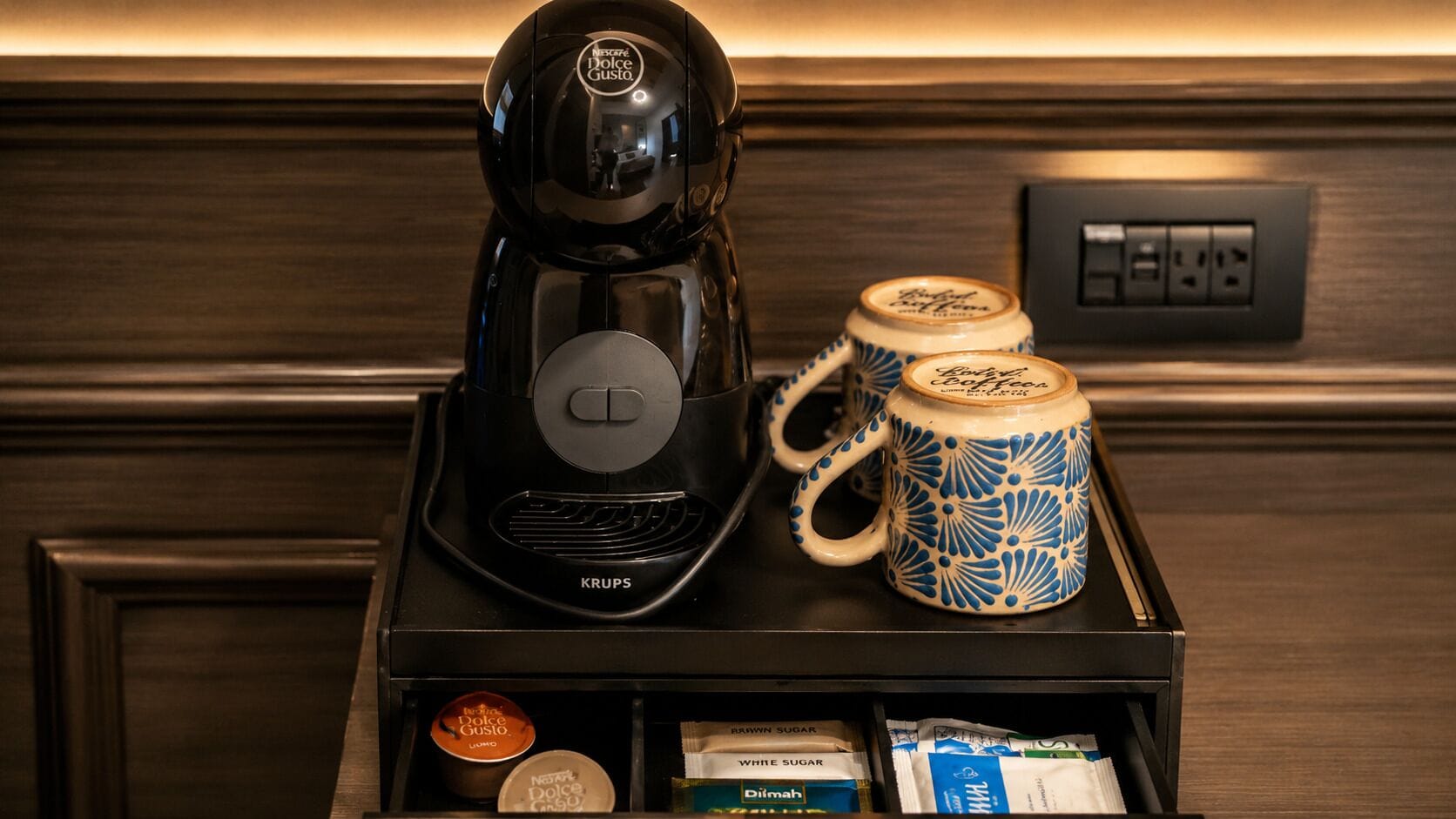 A coffee maker, a mug, and a tray with coffee pods and sugar packets.