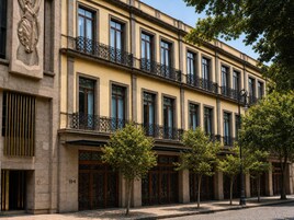 Un immeuble à plusieurs étages, doté d’une façade de style classique, de grandes fenêtres et d’un balcon orné de rampes en métal ouvragé.