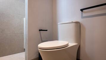 A modern bathroom with a white toilet, a black grab bar, and a tiled floor.