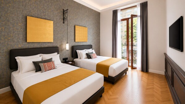 Habitación de hotel con dos camas, un ventanal con cortinas, un televisor de pantalla plana y obras de arte en las paredes.