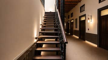 Una escalera con escalones de madera y barandilla de metal, que lleva a una plataforma con alfombra estampada.