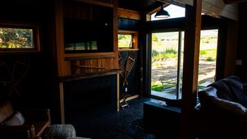 A cozy room with a fireplace, wooden furniture, and a view of the outdoors.