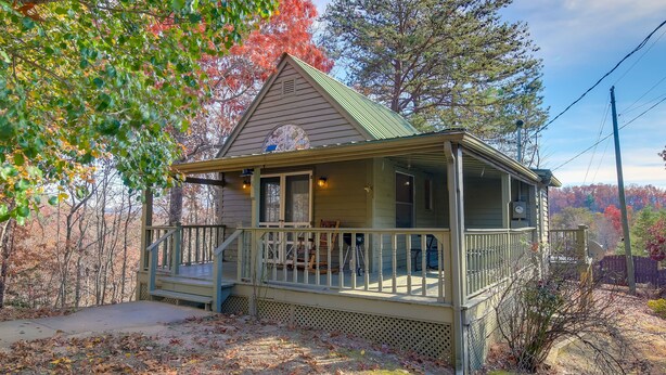 A cabin with a porch, a small deck, and a view of the surrounding trees.