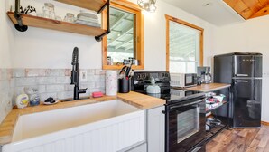 A modern kitchen with a wooden countertop, stainless steel appliances, and a large window.