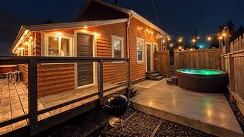 Eine Holzhütte mit Whirlpool, Terrasse und Lichterketten.