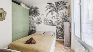 A bedroom with a bed, a green wall, a radiator, and a window with curtains. - Appart T2 Cosy et Chaleureux au coeur du 11eme (Paris)