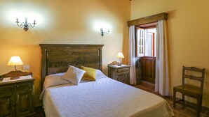 A bedroom with a wooden headboard, two bedside tables with lamps, a chair, and a window with curtains. - Countryside Views House Teror 1 (Teror)