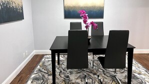 A dining area with a table and chairs, a vase with flowers, and a painting on the wall. - GP22B Spacious 2BD Condo | Pool | Grand Prairie (Grand Prairie)