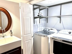 A laundry area with a washing machine, dryer, and shelves for hanging clothes.
