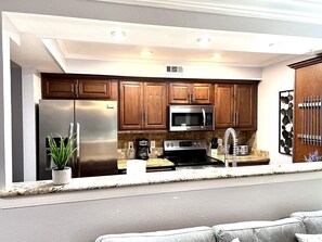A modern kitchen with stainless steel appliances, wooden cabinets, and a built-in microwave.