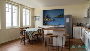 Una cocina moderna con una mesa de comedor de madera, taburetes de bar y una pared de acento azul.