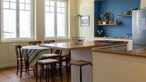 Una cocina moderna con una isla central, taburetes de bar y un comedor con mesa y sillas.