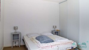 Ein kleines, sauberes Zimmer mit einem Bett, zwei Nachttischen und einem Beistelltisch.