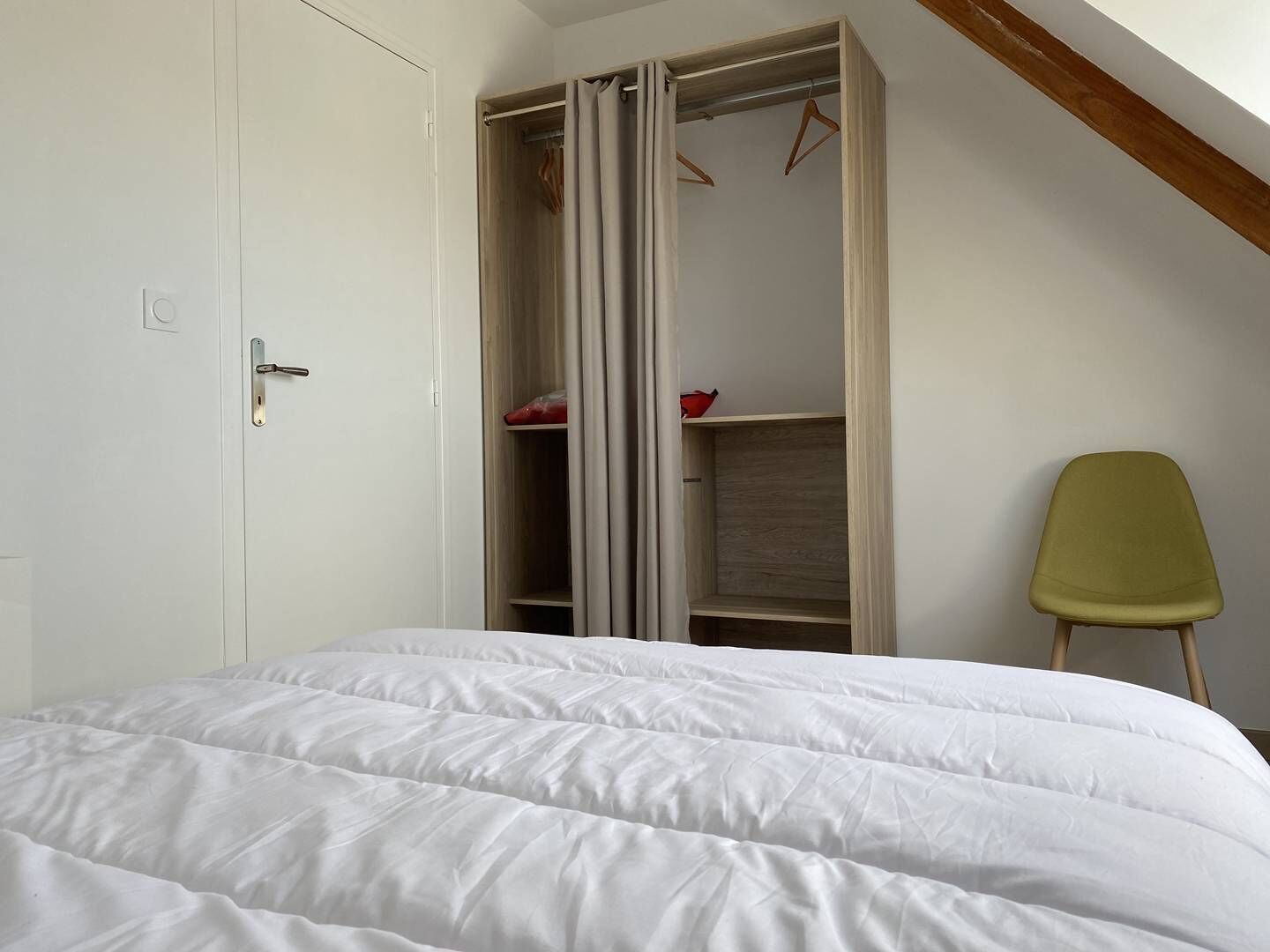 A bedroom with a bed, a wardrobe, and a chair.