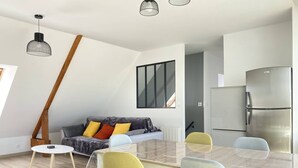 A modern kitchen with a stainless steel refrigerator, a dining table with chairs, and a grey sofa with colorful cushions. - Family apartment with terrace in Fréhel | 6 guests | Ref 303 (FREHEL)