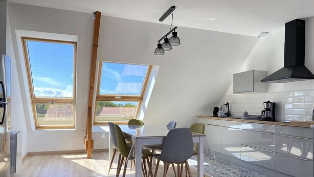 A modern kitchen with a dining area, large windows, and a loft-style ceiling. - Family apartment with terrace in Fréhel | 6 guests | Ref 303 (FREHEL)