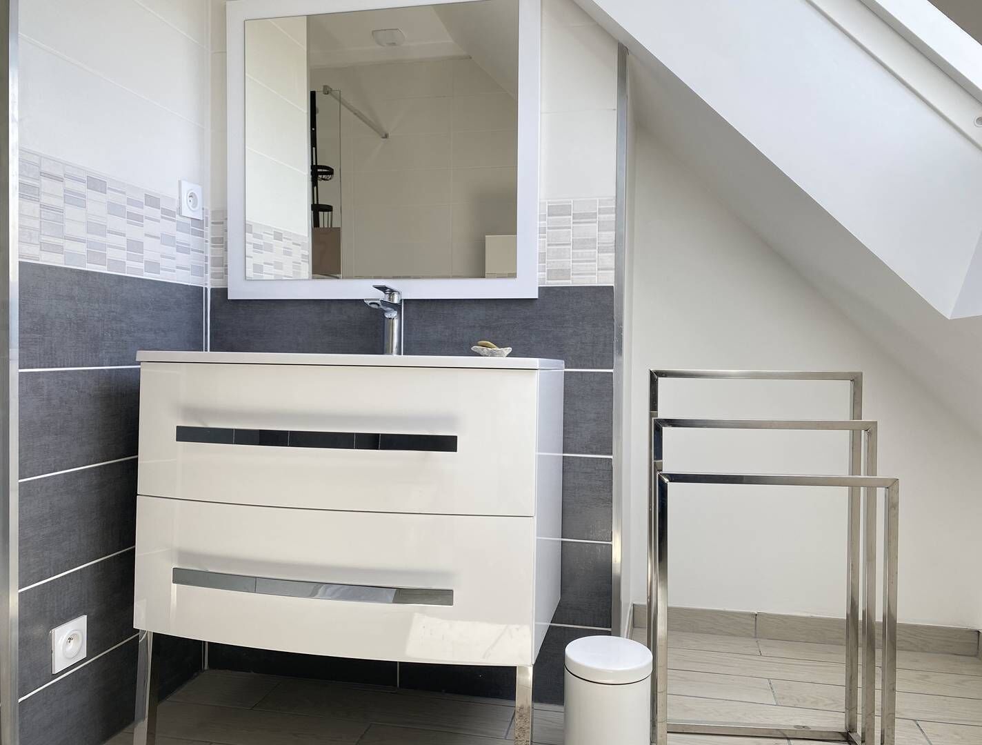 Une salle de bain moderne avec un meuble-lavabo blanc, un miroir et un espace douche.