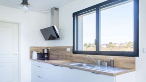 Una cocina moderna con un ventanal grande, una estufa empotrada y una cafetera.