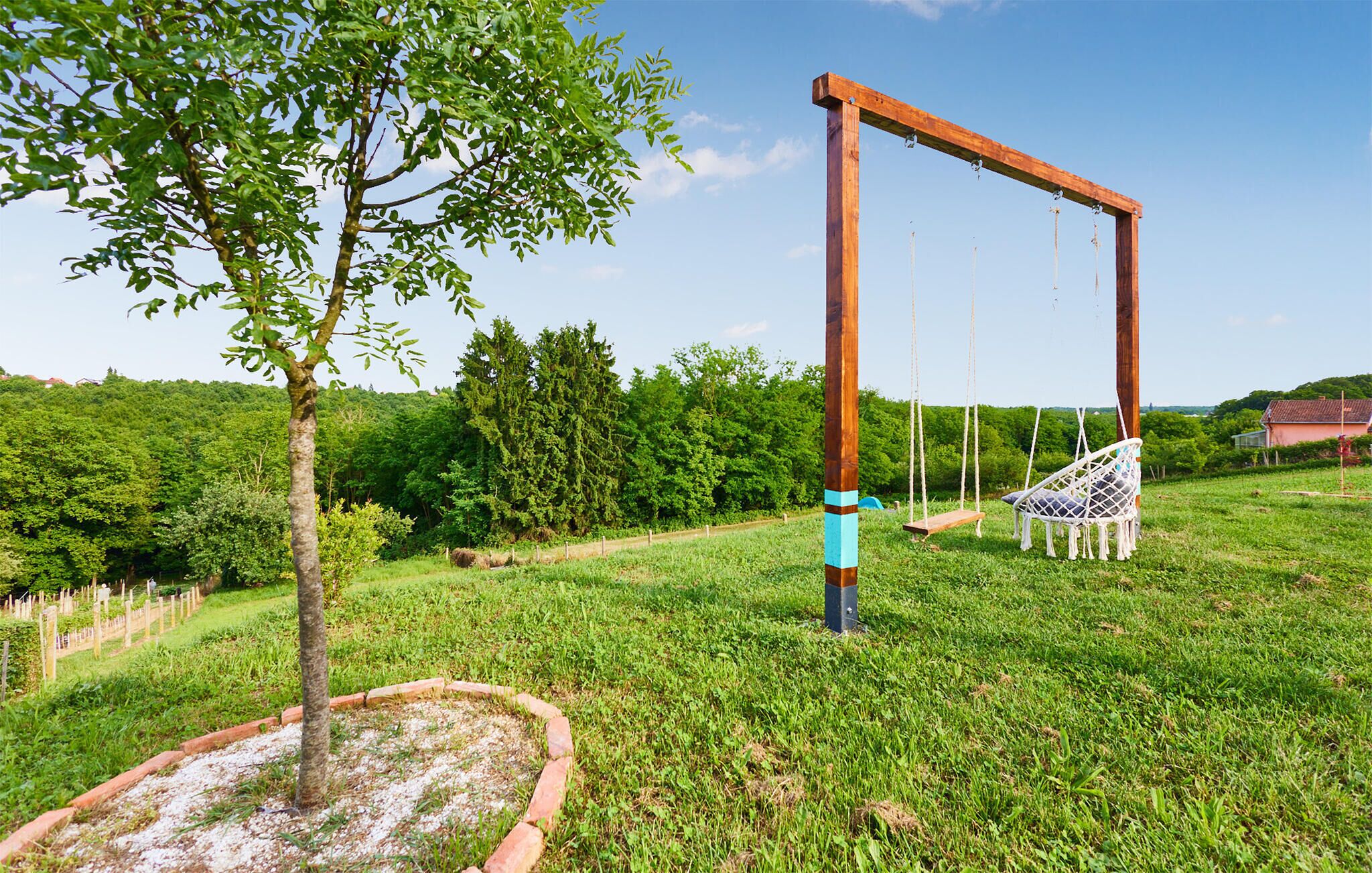 A wooden swing set in a grassy area with a tree nearby.